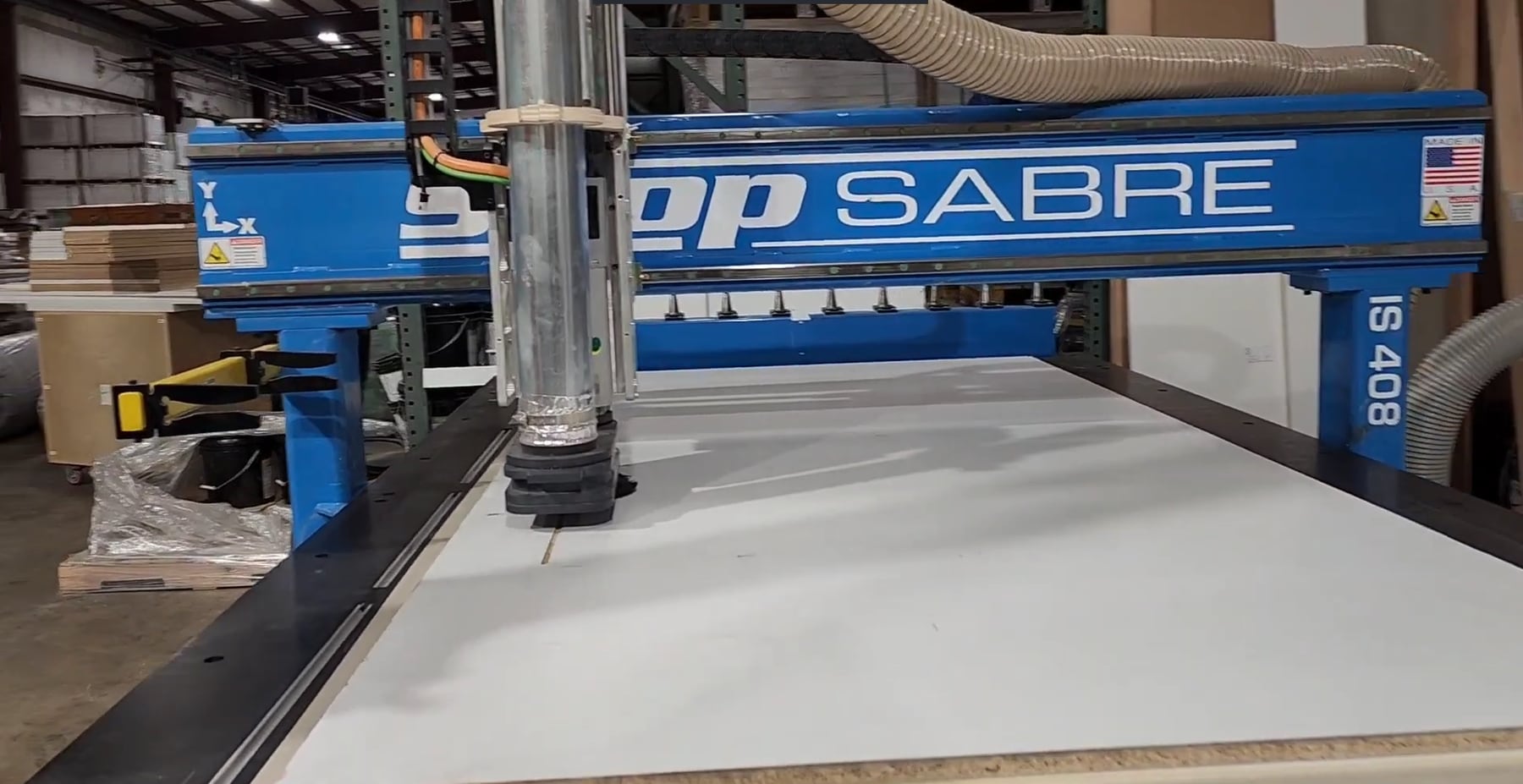 A CNC router cutting and drilling a white cabinet panel