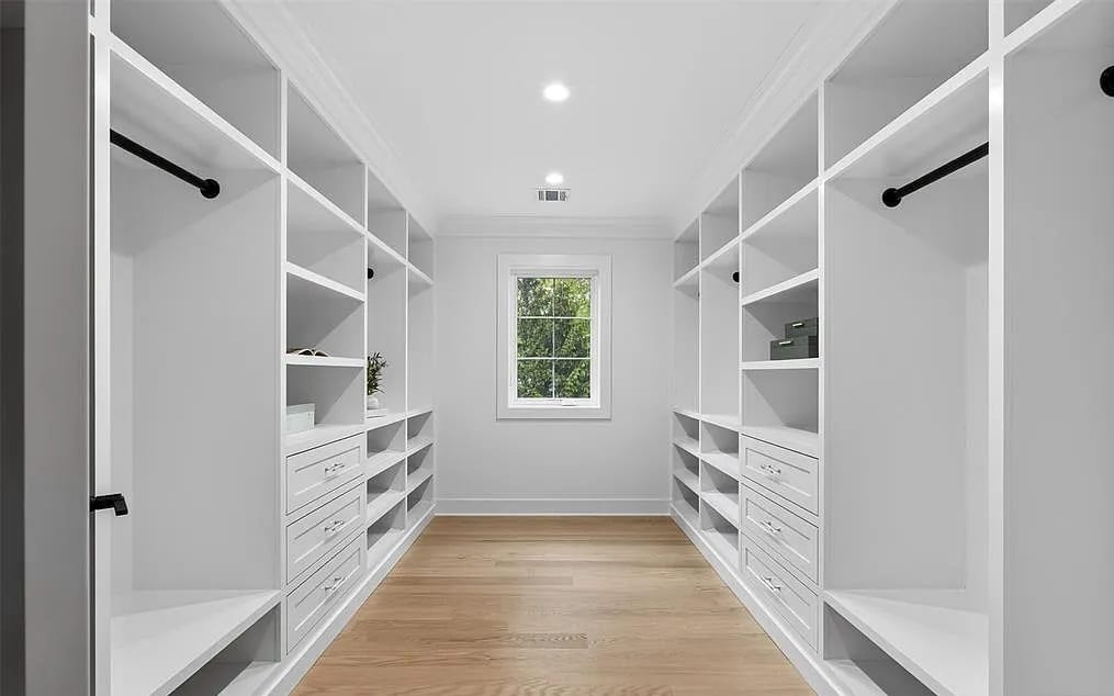 A white and oak walk-in with a bank of drawers under a cabinet at the far end